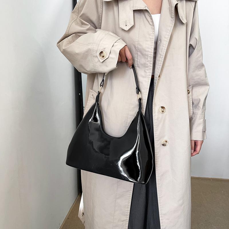 Woman holding a small black glossy leather bag