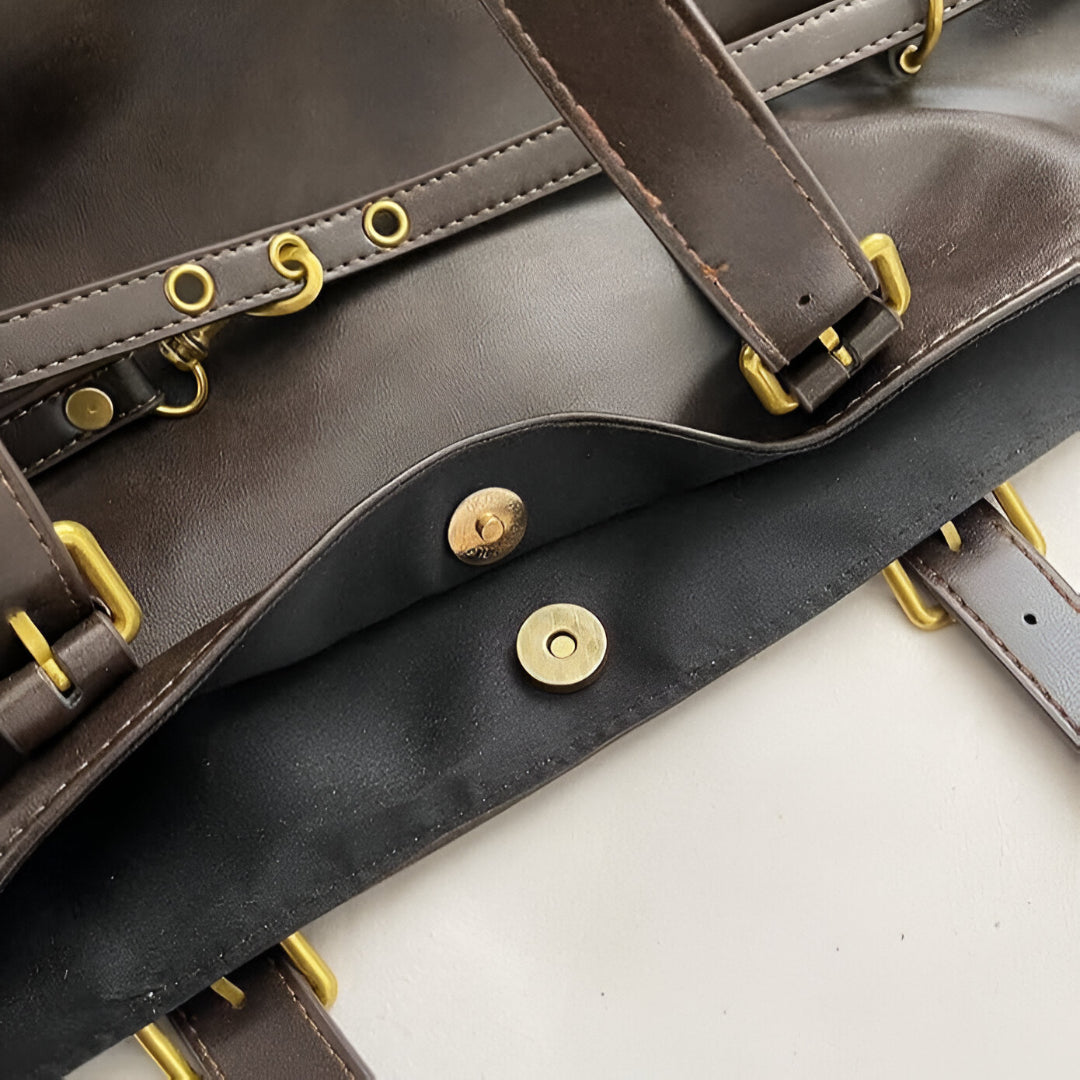 Close-up of a leather bag showing its magnetic snap closure and gold hardware