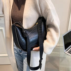 Woman holding a black crocodile-patterned leather handbag 