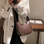 Woman wearing a black crocodile-patterned leather crossbody bag